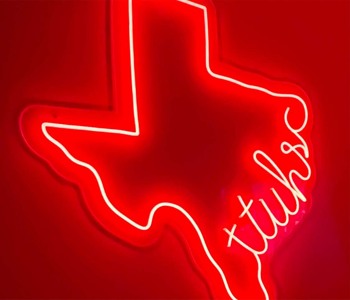 a neon sign in the shape of Texas with ttuhsc in script along the gulf coast outline